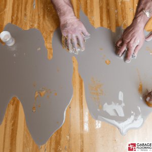 Hands making a mess with DIY epoxy garage floor installation